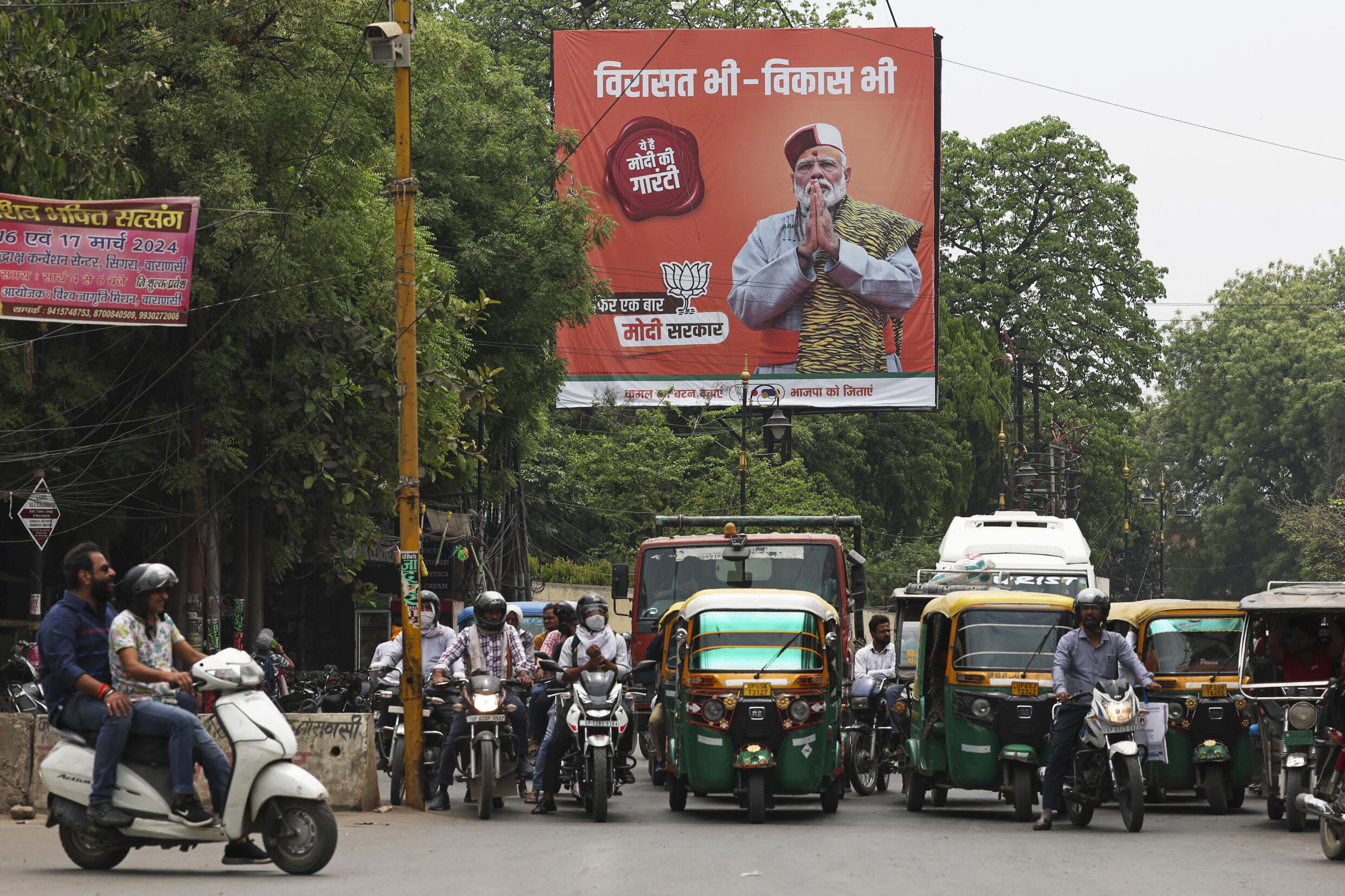 Des véhicules circulent et passent à côté d'un poster de campagne du BJP, le parti du Premier ministre, Narendra Modi, en tête de l'affiche, en lice pour les élections générales, à Varanasi, en Inde, le 13 avril 2024.