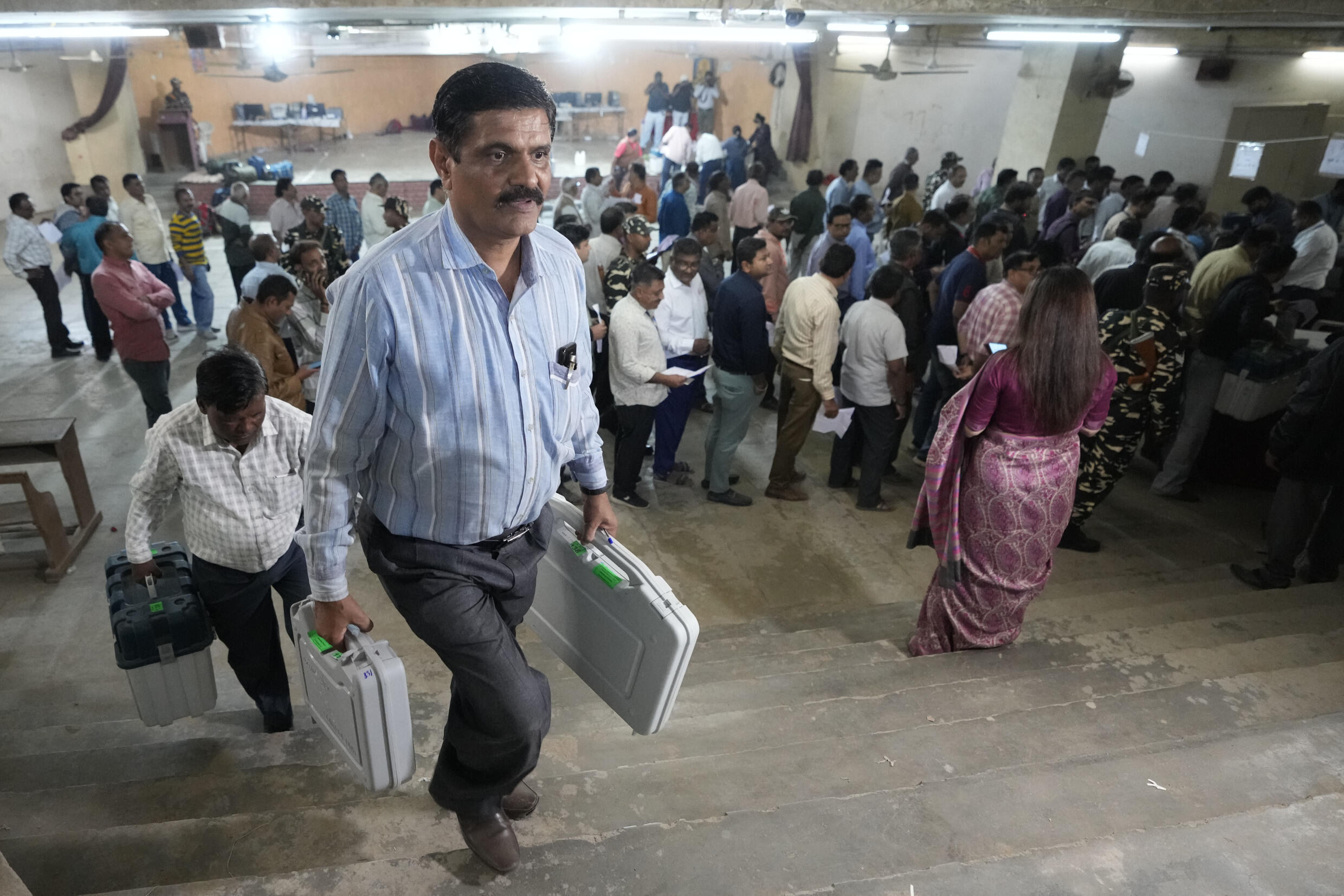 Les responsables électoraux munis de machines à voter électroniques partent pour leurs bureaux de vote dépendent à la veille de la phase suivante des élections législatives de l'État du Gujarat à Ahmedabad, en Inde, ce dimanche 4 décembre 2022.
